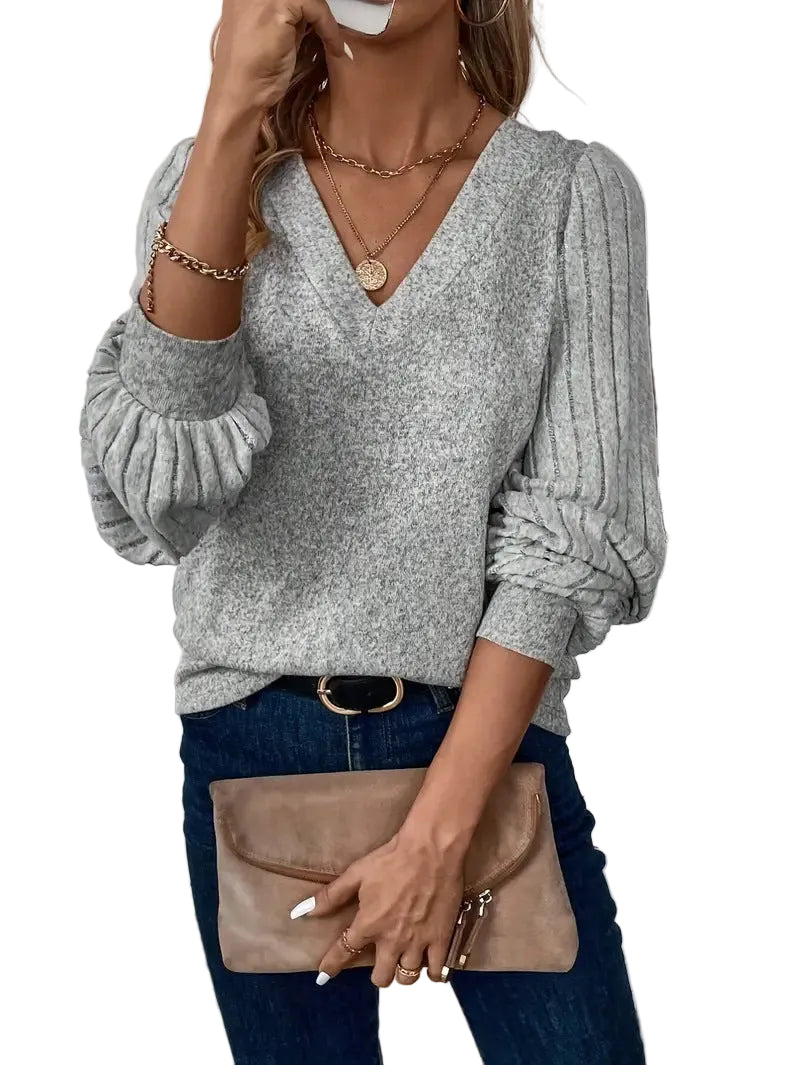 Pull col V gris chiné porté avec un jean et une pochette