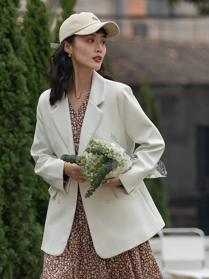 Blazer croisé blanc cassé porté sur une robe fleurie